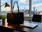 Black tote on a desk with a cityscape view through large windows